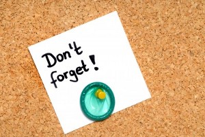 A condom and a note saying "Don't forget!" pinned to a pinboard